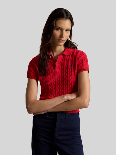 Frauenmodel trägt Regular Fit Strick-Poloshirt aus reiner Baumwolle von Polo Ralph Lauren in Rot mit Zopfmuster, Nahaufnahme Oberkörper.