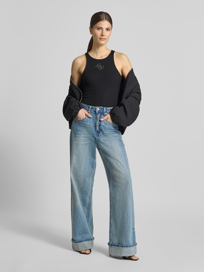 Modelka nosi Tanktop in Ripp-Optik mit Logo od Guess, mieszanka materiałów z dodatkiem streczu, krój slim fit, efekt prążkowania, logo, długość tyłu w rozmiarze S: 50 cm, widok całej sylwetki z przodu.