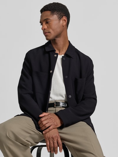 Männermodel trägt Regular Fit Overshirt mit Brusttaschen von MCNEAL, Material-Mix mit Stretch-Anteil, Kentkragen, Druckknopfverschluss, Sportmanschetten, Rückenlänge bei Größe M 73 cm, dezente Farben, glatte Textur, Nahaufnahme Oberkörper.