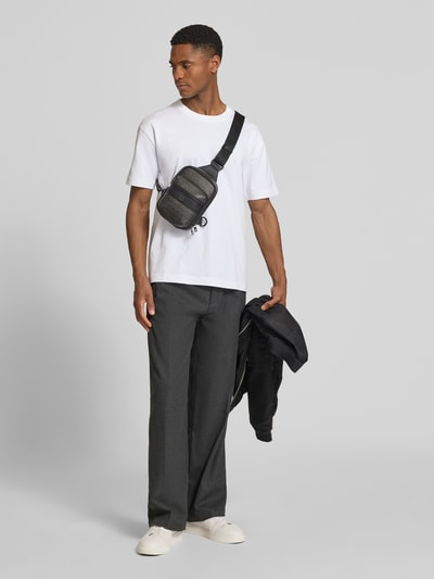 Männermodel trägt Umhängetasche mit Label-Muster Modell 'QUANTIC_M_MONOSTRAP' von HUGO, Optik:Allover-Muster, Logo-Applikation, Ganzkörperansicht von vorne.