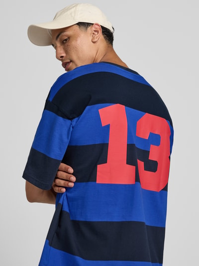 Männermodel trägt Oversized T-Shirt mit Label-Stitching von REVIEW, Allover-Look, Reine Baumwolle, Rundhalsausschnitt, Rückenlänge 67 cm, Ganzkörperansicht Rückansicht.