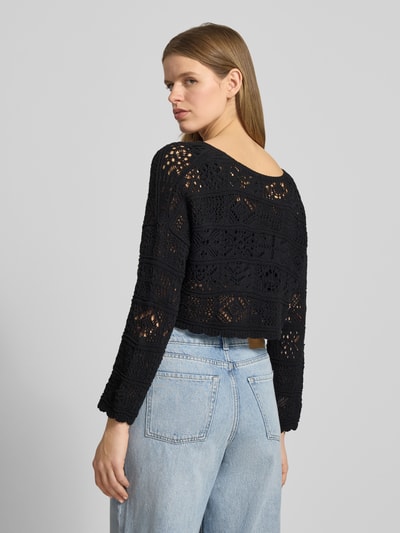 Frauenmodel trägt Cropped Strickjacke aus recyceltem Baumwoll-Mix Modell 'BEACH LIFE' von Only in Schwarz mit Lochstrickmuster, Ganzkörperansicht Rückansicht.