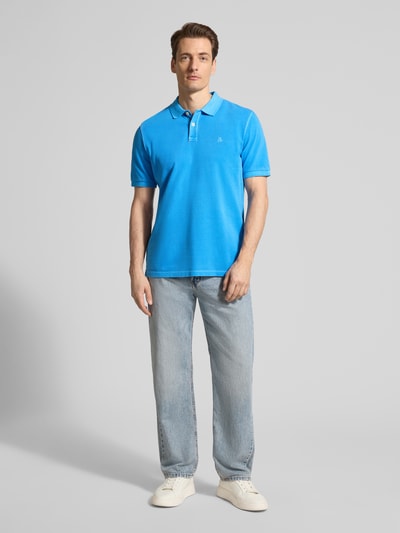 Männermodel trägt Regular Fit Poloshirt aus reiner Baumwolle von Marc O'Polo, unifarbenes Piqué in Blau, Ganzkörperansicht von vorne.