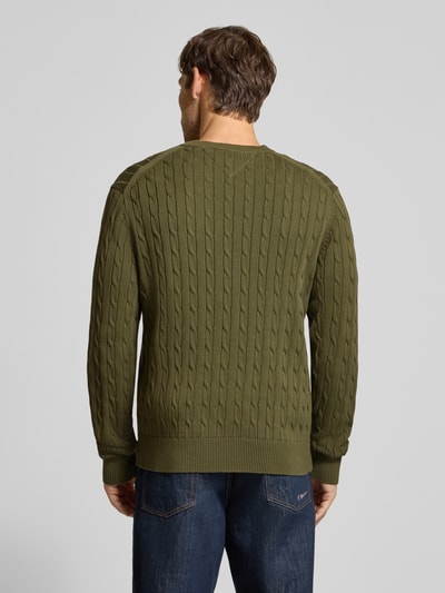 Mężczyzna model nosi Regular Fit Pullover aus reiner Baumwolle von Tommy Hilfiger, oliwkowa z fakturą warkocza, Ganzkörperansicht Rückansicht.