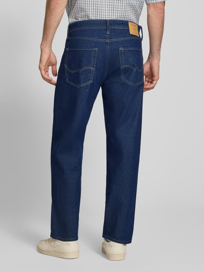 Männermodel trägt Loose Fit Jeans im 5-Pocket-Design Modell 'EDDIE' von JACK & JONES, blaue Baumwolle, Label-Patch, Ganzkörperansicht Rückansicht.