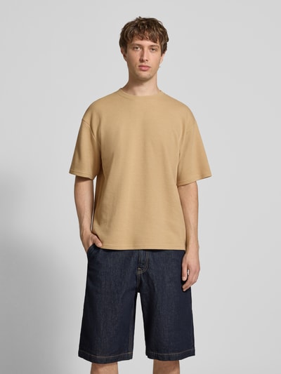 Männermodel trägt T-Shirt mit Strukturmuster und Rundhalsausschnitt Modell 'PETER' von Redefined Rebel in Beige, Relaxed Fit, Ganzkörperansicht von vorne.