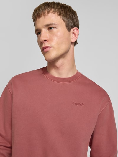 Männermodel trägt Sweatshirt mit Logo-Stitching und Rundhalsausschnitt von Levi's®, rostrote Farbe, reine gewachste Baumwolle, Nahaufnahme Oberkörper.