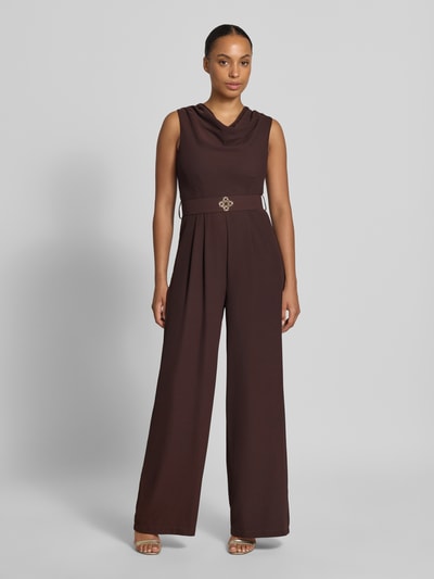 Frauenmodel trägt Jumpsuit mit Neckholder von Rinascimento in Dunkelbraun, taillierte Passform, Stoffgürtel, Material-Mix, Ganzkörperansicht von vorne.