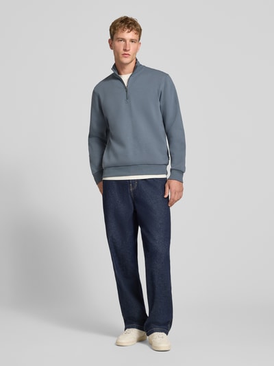 Männermodel trägt Regular Fit Sweatshirt mit Baumwoll-Anteil Modell 'Bradley' von JACK & JONES in Blau, glatte Textur, Troyer-Kragen, Ganzkörperansicht von vorne. Rückenlänge 68 cm, Ärmellänge 66 cm.