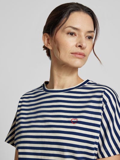 Kobiece modelka nosi damski t-shirt z wzorem w paski, haft, okrągły dekolt, model 'Salentine stripe' od OPUS z bawełny, krój regular fit, długość tyłu w rozmiarze 36: 56 cm, zbliżenie na górną część ciała.