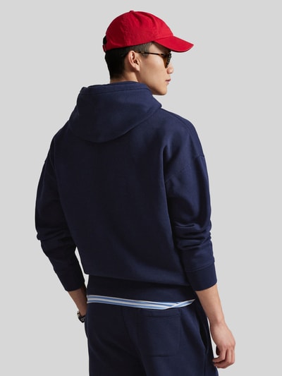 Männermodel trägt Relaxed Fit Hoodie aus Baumwoll-Mix von Polo Ralph Lauren in Dunkelblau mit Kapuze und Kängurutasche, Ganzkörperansicht Rückansicht.