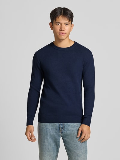 Männermodel trägt Strickpullover aus reiner Baumwolle Modell 'Ryder' von JACK & JONES in Dunkelblau, dezente Strick-Optik, Ganzkörperansicht von vorne