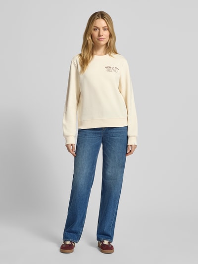 Vrouwenmodel draagt sweatshirt met labelprint en ronde hals van Scotch & Soda, puur katoen, regular fit, crèmekleurig, full body vooraanzicht.