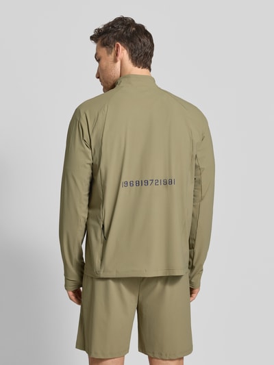 Männermodel trägt Funktionsshirt mit Stehkragen und Reißverschluss Modell 'AIR' von HALO, regular fit, stretch, label-print, olijfgroen, materiaal-mix, ruglengte 70 cm bij maat M, Ganzkörperansicht Rückansicht.