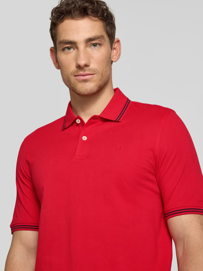 Männermodel trägt Regular Fit Poloshirt mit Logo-Stitching von bugatti in Rot, Baumwolle mit Polokragen, Nahaufnahme Oberkörper.