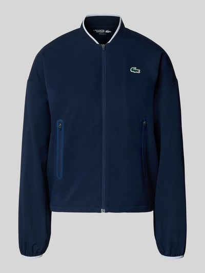Produktfoto, Regular Fit Trainingsjacke mit Baseball-Kragen von Lacoste Sport in Dunkelblau, unifarben, elastische Ärmelabschlüsse, Reißverschlusstaschen, glatte Textur