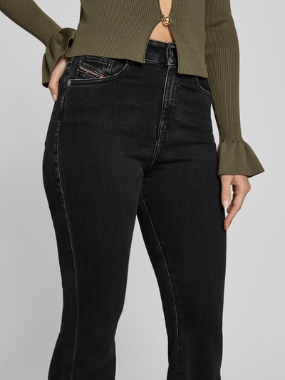 Frauenmodel trägt Flared Fit Jeans mit Logo-Detail von Diesel aus schwarzem Baumwoll-Mix im 5-Pocket-Design, Nahaufnahme Oberkörper.