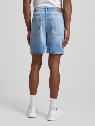 Männermodel trägt Loose Fit Jeansshorts aus Baumwoll-Lyocell-Mix Modell 'ALEX' von SELECTED HOMME, 5-Pocket, Label Patch, Denim-Optik, Ganzkörperansicht Rückansicht.