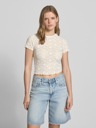 Frauenmodel trägt Slim Fit T-Shirt aus Spitze Modell 'FAITH' von Only in Unifarben mit Spitzenmuster und Frill-Details, Ganzkörperansicht von vorne.