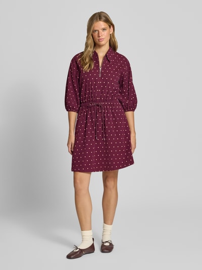 Vrouwenmodel draagt 'Tailliertes Freizeitkleid aus reiner Baumwolle' van MOP DENIM in bordeaux met witte stippen, hemdkraag, 3/4-mouw met elastische boord, tailleband en uitlopende rok, geheel van katoen, allover patroon, volledig zicht van voren.