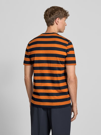 Männermodel trägt Regular Fit T-Shirt mit Logo-Stitching von Christian Berg Men, orange-schwarz gestreift, Reine Baumwolle, Rückenlänge 70 cm, Ganzkörperansicht Rückansicht.