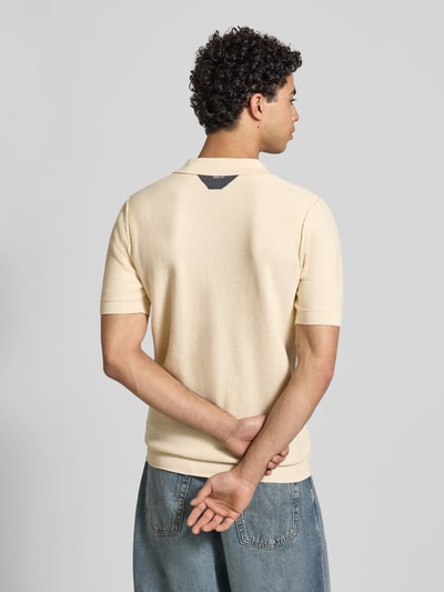 Męski model nosi Slim Fit Poloshirt in Strick-Optik od Replay, kolor jasny, krój slim fit, krótki rękaw, bawełna, tekstura dzianiny, widoczna kieszeń, detal z logo, długość tyłu w rozmiarze M: 69 cm. Ganzkörperansicht Rückansicht.