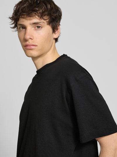 Männermodel trägt T-Shirt mit Rundhalsausschnitt Modell 'EURBAN EDGE' von Jack & Jones in Schwarz, reine Baumwolle, Nahaufnahme Oberkörper.