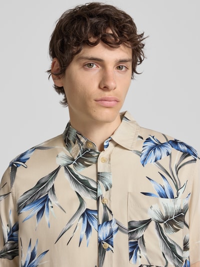 Männermodel trägt Regular Fit Freizeithemd aus Viskose Modell 'AMELO' von Blend mit Allover-Blumenmuster in Beige, Blau und Schwarz, Nahaufnahme Oberkörper.