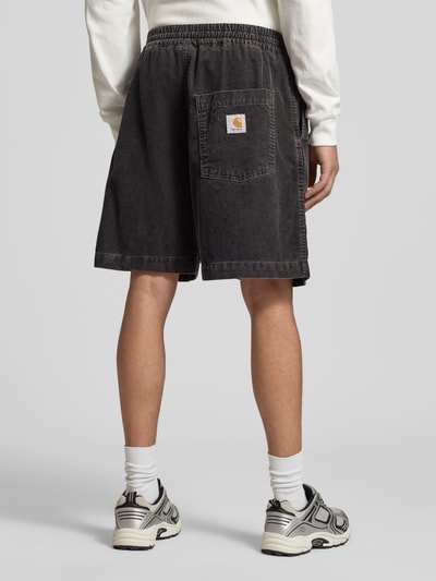 Mężczyzna nosi Jeansshorts mit elastischem Bund Modell 'Reynold' von Carhartt Work In Progress, bawełna, krój relaxed fit, czarny, szerokość w rozmiarze M 41 cm, długość nogawki wewnętrznej 18 cm, widok całej sylwetki z tyłu.