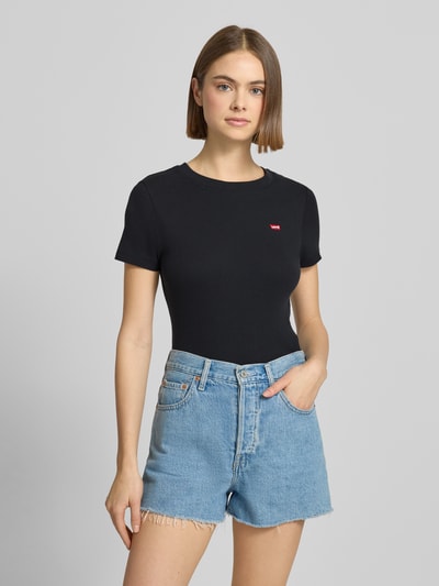 Modelka nosi czarne T-Shirt z bawełny marki Levi's®, prosty fason, czerwony label-patch, okrągły dekolt, model 'Cavia', z przodu widok na cały tułów