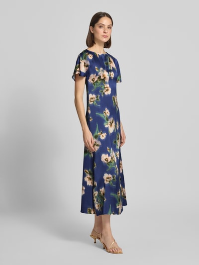 Frauenmodel trägt Cocktailkleid in Midilänge Modell 'Leonie' von GUIDO MARIA KRETSCHMER WOMAN aus Satin mit floralen Prints, A-Linie, kurzärmelig, Rundhalsausschnitt, Schlüsselloch-Ausschnitt hinten, Ganzkörperansicht von vorne.