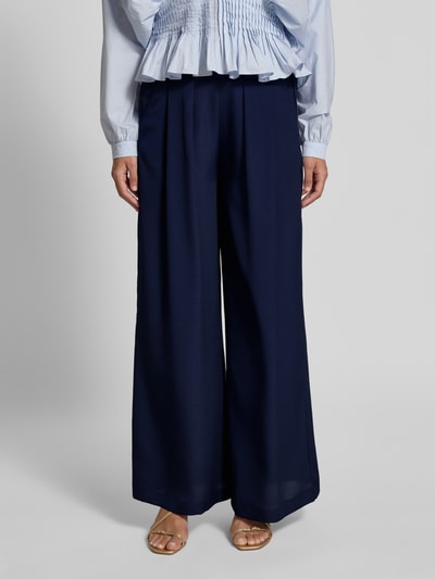 Frauenmodel trägt Wide Leg Hose mit elastischem Bund von Rich & Royal in Dunkelblau, mit Gelegten Falten und Eingrifftaschen, Nahaufnahme Oberkörper.