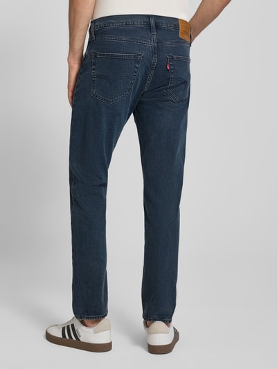 Männermodel trägt Tapered-Fit Jeans aus Baumwoll-Mix Modell '502™ TAPER' von Levi's® in dunklem Blau mit Taschenstruktur, Ganzkörperansicht Rückansicht. Herren Tapered Fit Jeans von Levi's®.