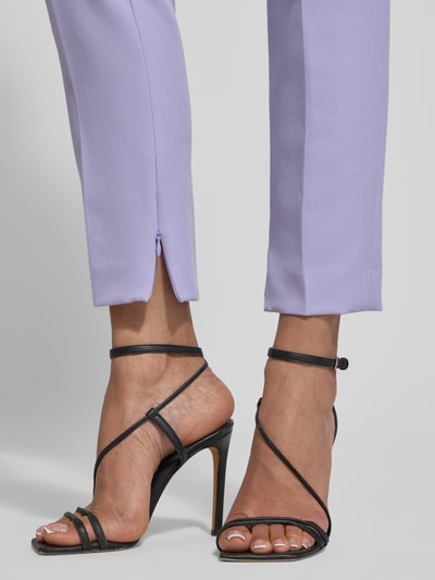 Frauenmodel trägt Slim Fit Schmale Hose mit Label-Applikation Modell 'HEDIMA-1' von HUGO, fliederfarben, Beinabschluss mit Reißverschluss, Detailaufnahme Unterschenkel.