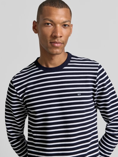 Männermodel trägt Regular Fit Langarmshirt aus Baumwoll-Mix von Christian Berg Men, gestreift in Schwarz-Weiß, Nahaufnahme Oberkörper. Baumwoll-Mix, elastische Ärmelabschlüsse, Rundhalsausschnitt, Rückenlänge bei Größe M 72 cm.