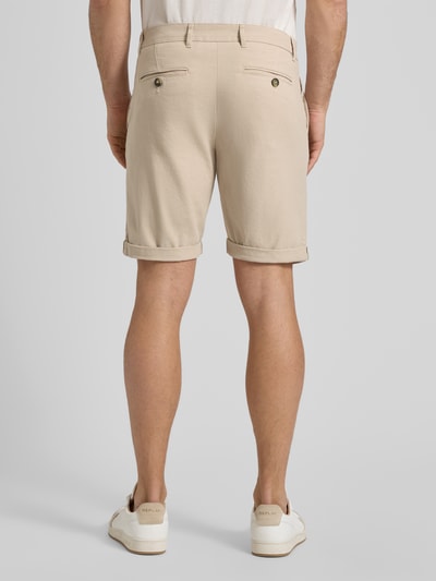 Männermodel trägt Slim Fit Chinoshorts aus Baumwoll-Mix Modell 'SLIM-LUTON' von SELECTED HOMME, efekt: jednolity kolor, aplikacja z metką, szlufki na pasek, zapięcie na guzik i zamek błyskawiczny, wpuszczane kieszenie, kieszenie z tyłu z guzikiem, wykończenie materiału: tkana faktura, mieszanka bawełny, krój slim fit, model męski, kolor beżowy, Ganzkörperansicht Rückansicht.