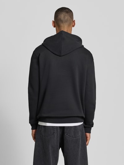 Mannelijk model draagt Hoodie met Logo-Detail en Känguru-Tasche van GAP in katoenmix, loose fit, geribde boorden, ruglengte 70 cm, mouwlengte 65 cm, Ganzkörperansicht Rückansicht.