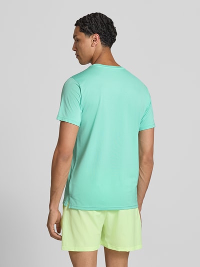 Männermodel trägt Funktionsshirt mit Rundhalsausschnitt und Logo von New Balance in Mint, Regular-Fit, Rückenlänge 69 cm, Ganzkörperansicht Rückansicht.