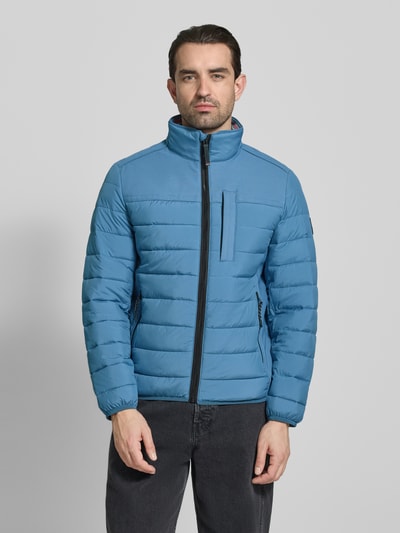 Männermodel trägt Regular Fit Steppjacke mit seitlichen Stretcheinsätzen von Tom Tailor, jednolity kolor, stójka, długi rękaw, zamek błyskawiczny, naszywka z logo, pas na plecach, elastyczne zakończenia, hydrofobowy, kieszeń wewnętrzna, boczne kieszenie na zamek, brustasza, krój regular fit, Ganzkörperansicht von vorne.
