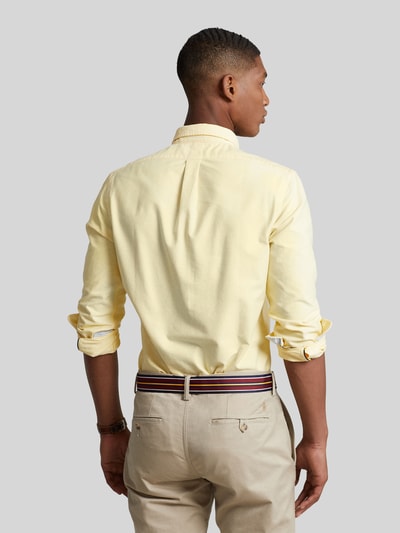 Männermodel trägt Slim Fit Freizeithemd aus reiner Baumwolle von Polo Ralph Lauren in Hellgelb, glatte Textur, Ganzkörperansicht Rückansicht.