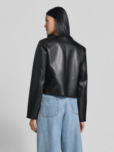 Frauenmodel trägt Jacke in Leder-Optik Modell 'LEONTINE' von GUESS, schwarze Farbe, strukturierte Oberfläche, Ganzkörperansicht Rückansicht. Damen Jacke mit Rundhalsausschnitt, Hakenverschluss, aufgesetzten Eingrifftaschen, Zierband-Stitchings, Rückenlänge 49 cm, Schulterbreite 39 cm, Brustweite 43 cm, Ärmellänge 63 cm.