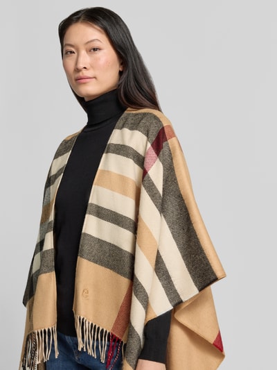 Frauenmodel trägt Relaxed Fit Poncho in Strick-Optik von FRAAS, Streifenmuster in Beige, Schwarz, Rot, Fransen, 3/4-Arm, Nahaufnahme Oberkörper.
