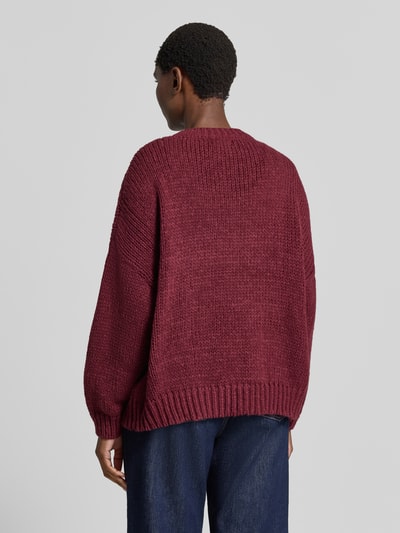 Frauenmodel trägt Oversized Strickpullover mit floralen Stitchings von Apricot, kolor bordowy, faktura dzianiny, prążkowane wykończenia, długość tyłu 62 cm, długość rękawów 43 cm, Ganzkörperansicht Rückansicht