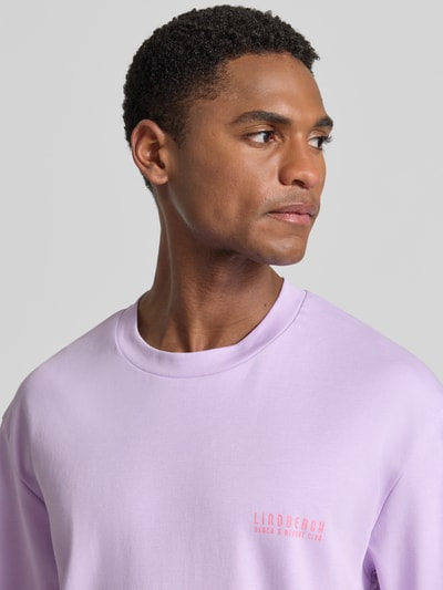 Männermodel trägt Oversized T-Shirt mit Label-Print von Lindbergh in Flieder, Reine Baumwolle, Rundhalsausschnitt, Nahaufnahme Oberkörper.