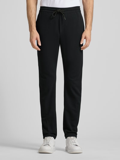 Männermodel trägt Tapered Chino mit Viskose-Anteil von Tom Tailor Denim, Optik: Unifarben, Passform: Tapered, Longline-Länge, Label-Stitching-Applikation, Tunnelzug-Verschluss, Bundabschluss elastisch, Beinabschluss fixierter Umschlag, Gesäßtaschen und seitliche Eingrifftaschen, Ganzkörperansicht von vorne.