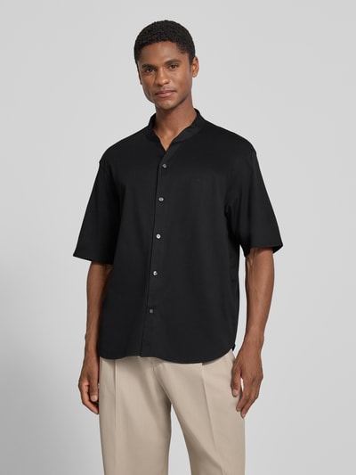 Männermodel trägt Regular Fit Freizeithemd mit V-Ausschnitt und Label-Stitching von Emporio Armani aus Reine Baumwolle in Schwarz, Ganzkörperansicht von vorne. Rückenlänge 74 cm, Schulterbreite 52 cm, Ärmellänge 27 cm, helle Hose als Kontrast.