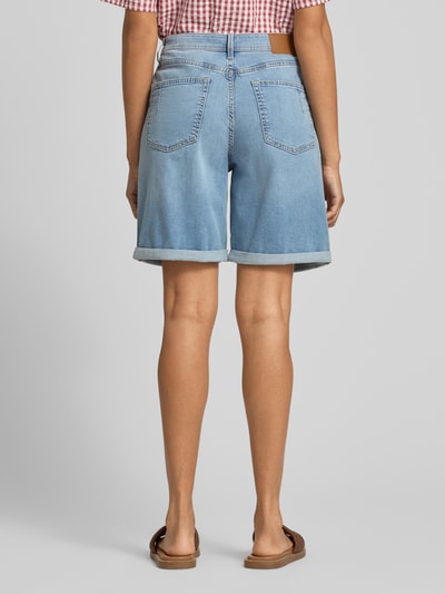 Vrouwenmodel draagt Regular Fit Jeansshorts uit katoenmix model 'SURI' van s.Oliver RED LABEL in lichtblauw denim met studs, label patch, riemlussen, knoop- en ritssluiting, omgeslagen zoom, 5-pocket-design; context: dames jeansshorts, detail: rechte pasvorm, merk: s.Oliver; volledige achterkantaanzicht.