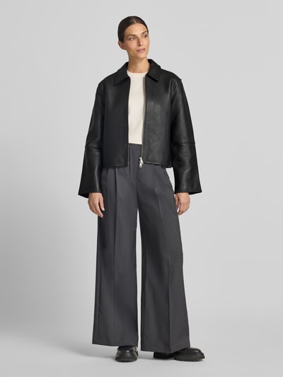 Frauenmodel trägt Relaxed Fit Jacke in Leder-Optik Modell 'SALYLO' von Samsøe Samsøe, schwarz, Umlegekragen, Zweiwege-Reißverschluss, Ganzkörperansicht von vorne.
