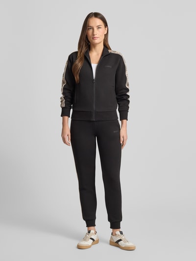 Frauenmodel trägt schwarze Sweatpants mit elastischem Bund Modell 'BRITNEY' von Guess Activewear, lockerer Schnitt, Ganzkörperansicht von vorne.