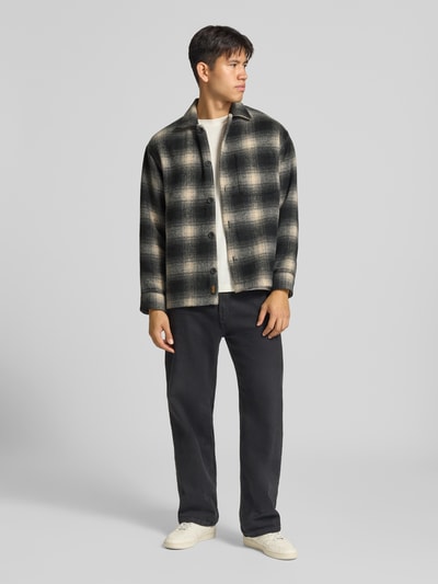 Männermodel trägt Regular Fit Hemdjacke mit Brusttasche Modell 'SOHO OLLIE' von JACK & JONES, kariertes Muster, Ganzkörperansicht von vorne. Kontext: Herren Hemdjacke von JACK & JONES, Kentkragen, durchgehende Knopfleiste, Rückenlänge 71 cm, Schulterbreite 41 cm, Ärmellänge 65 cm.